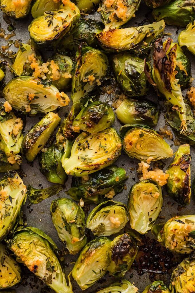 Crispy oven roasted Brussels sprouts with garlic and herbs, golden brown on a baking sheet.