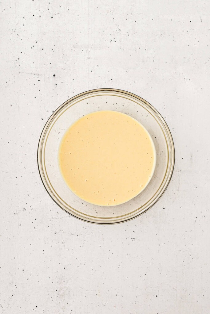 Glass bowl filled with creamy homemade apple coleslaw dressing made from mayonnaise, honey, mustard, and apple cider vinegar.