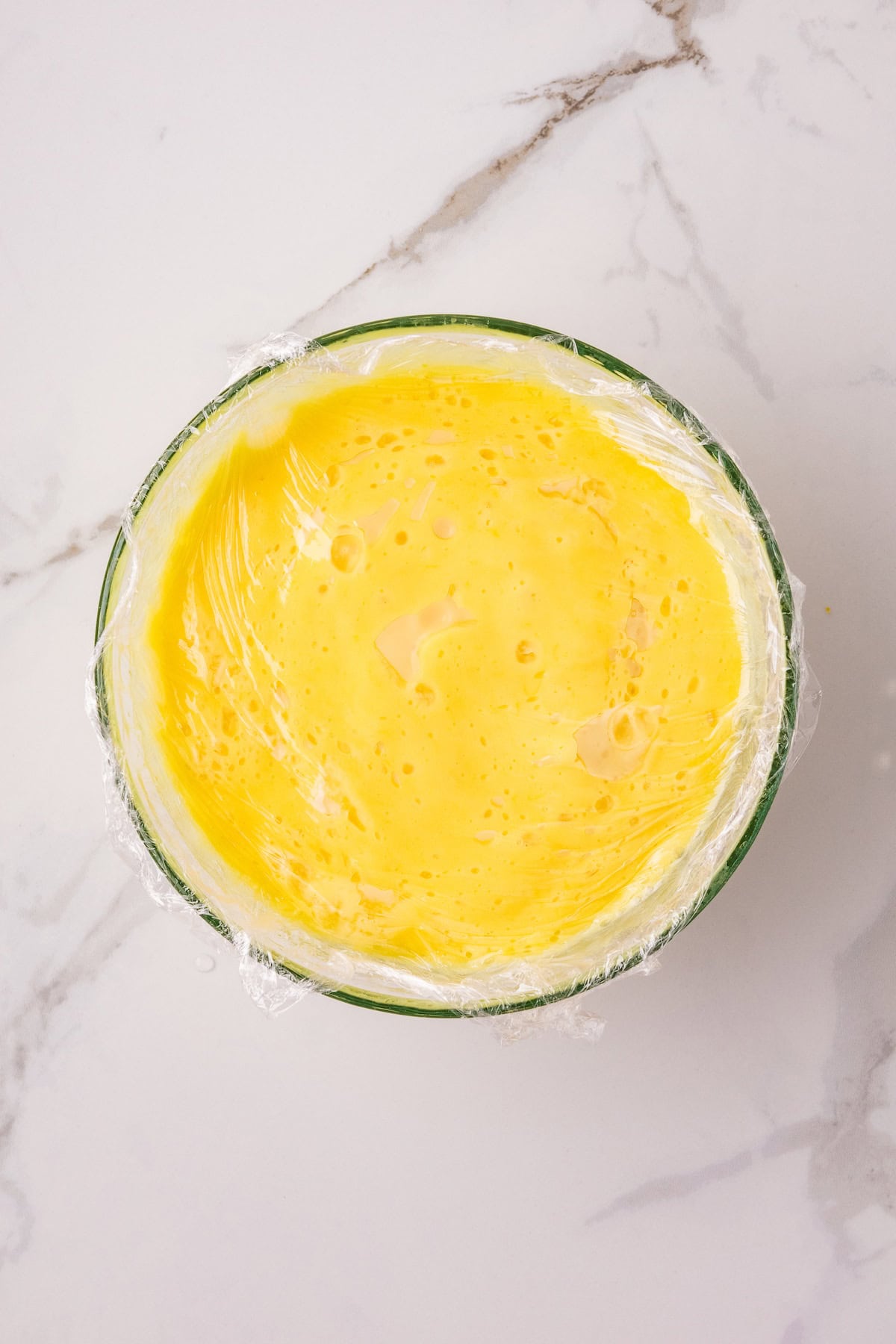 Instant Pot lemon curd covered with plastic wrap to prevent a skin from forming while chilling.