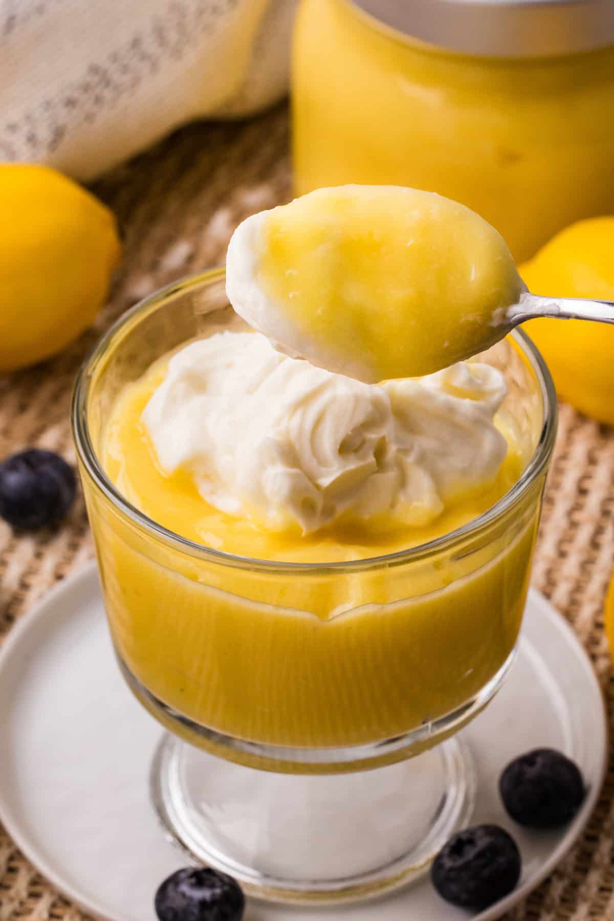Creamy Instant Pot lemon curd served with whipped cream in a glass dessert dish.