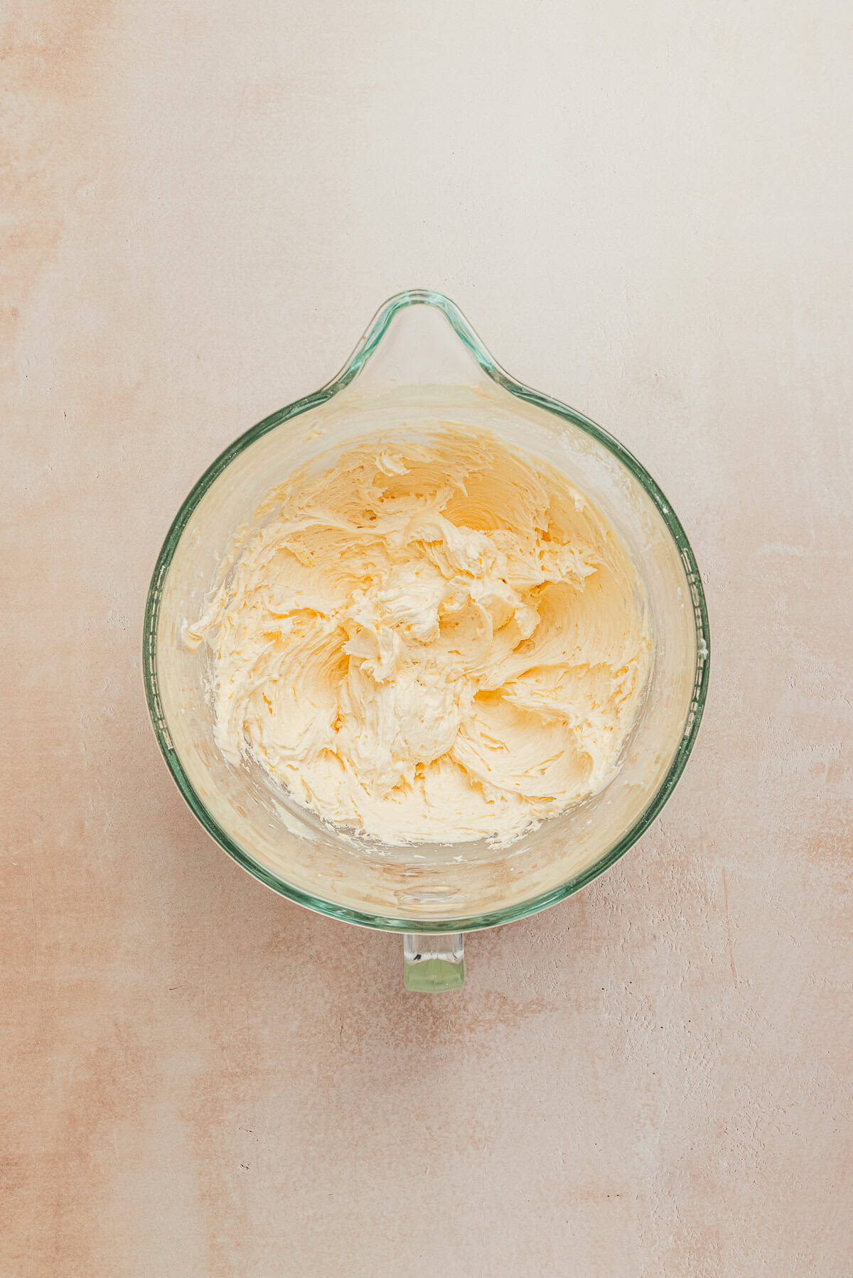 Creamy lemon buttercream frosting mixed in a glass bowl with a smooth texture.