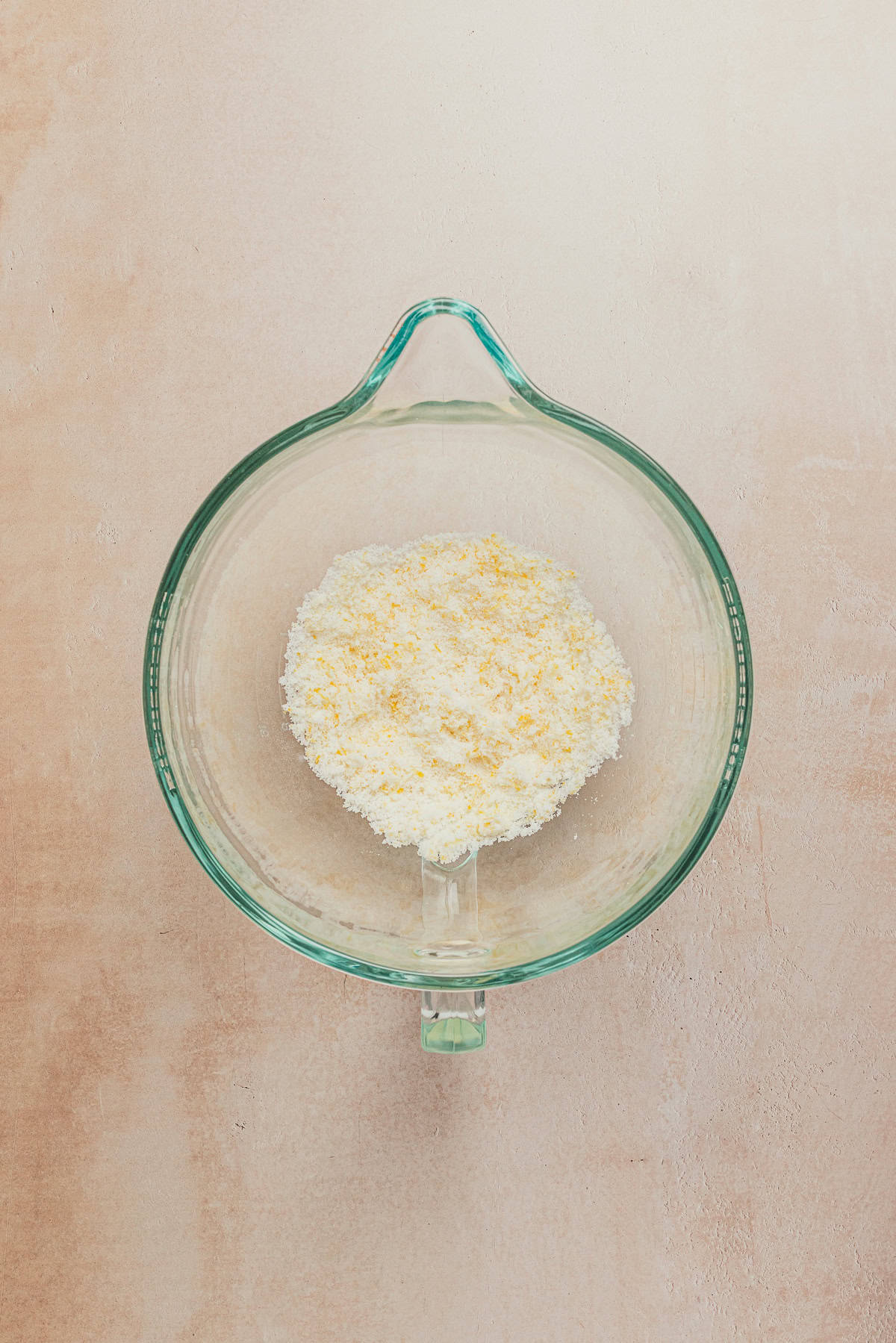 Sugar and lemon zest combined in a glass mixing bowl for lemon cookie dough.