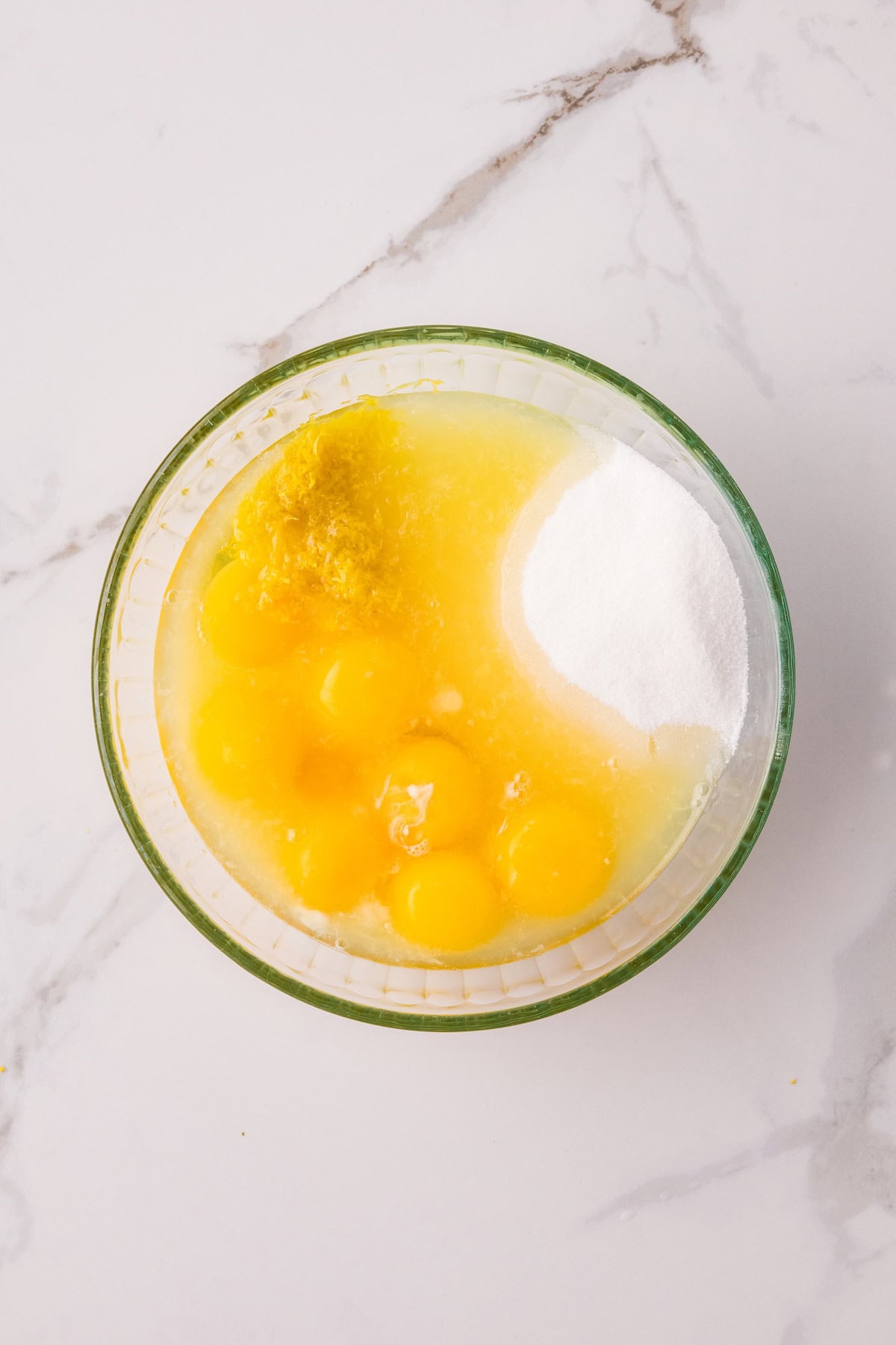 Eggs, sugar, lemon juice, and lemon zest combined in a bowl to make homemade lemon curd.