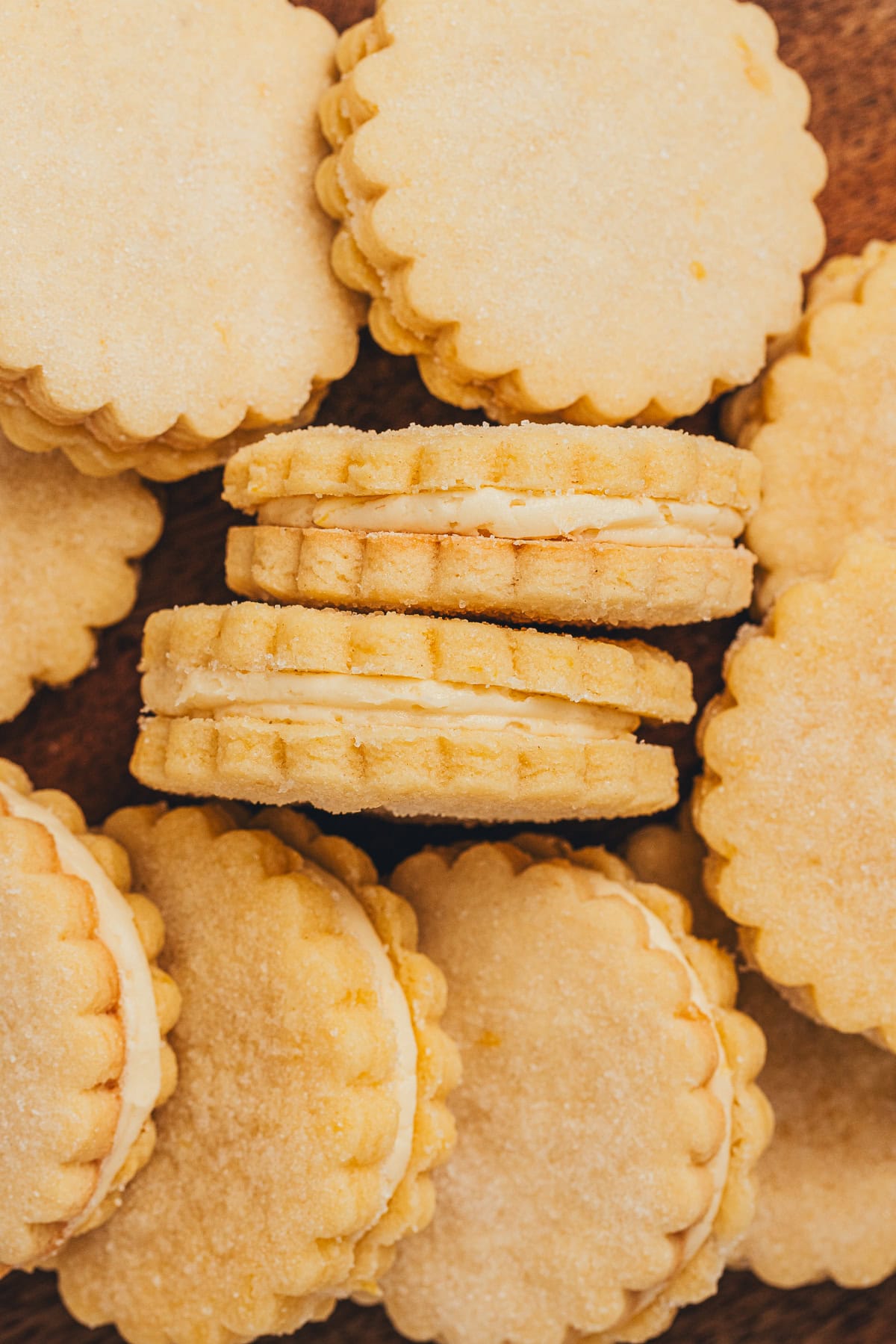 Top view of lemon sandwich cookies showing scalloped edges and smooth buttercream filling.