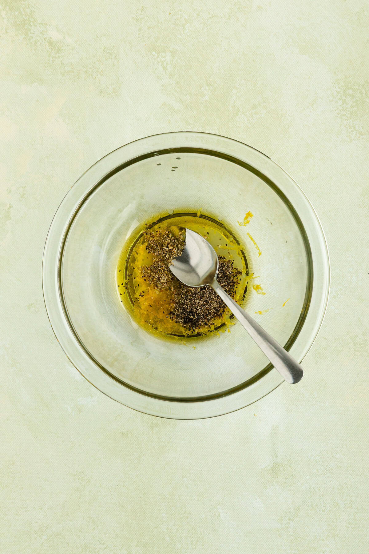 Olive oil, lemon juice, lemon zest, oregano, salt, and pepper mixed in a bowl to season roasted cauliflower.