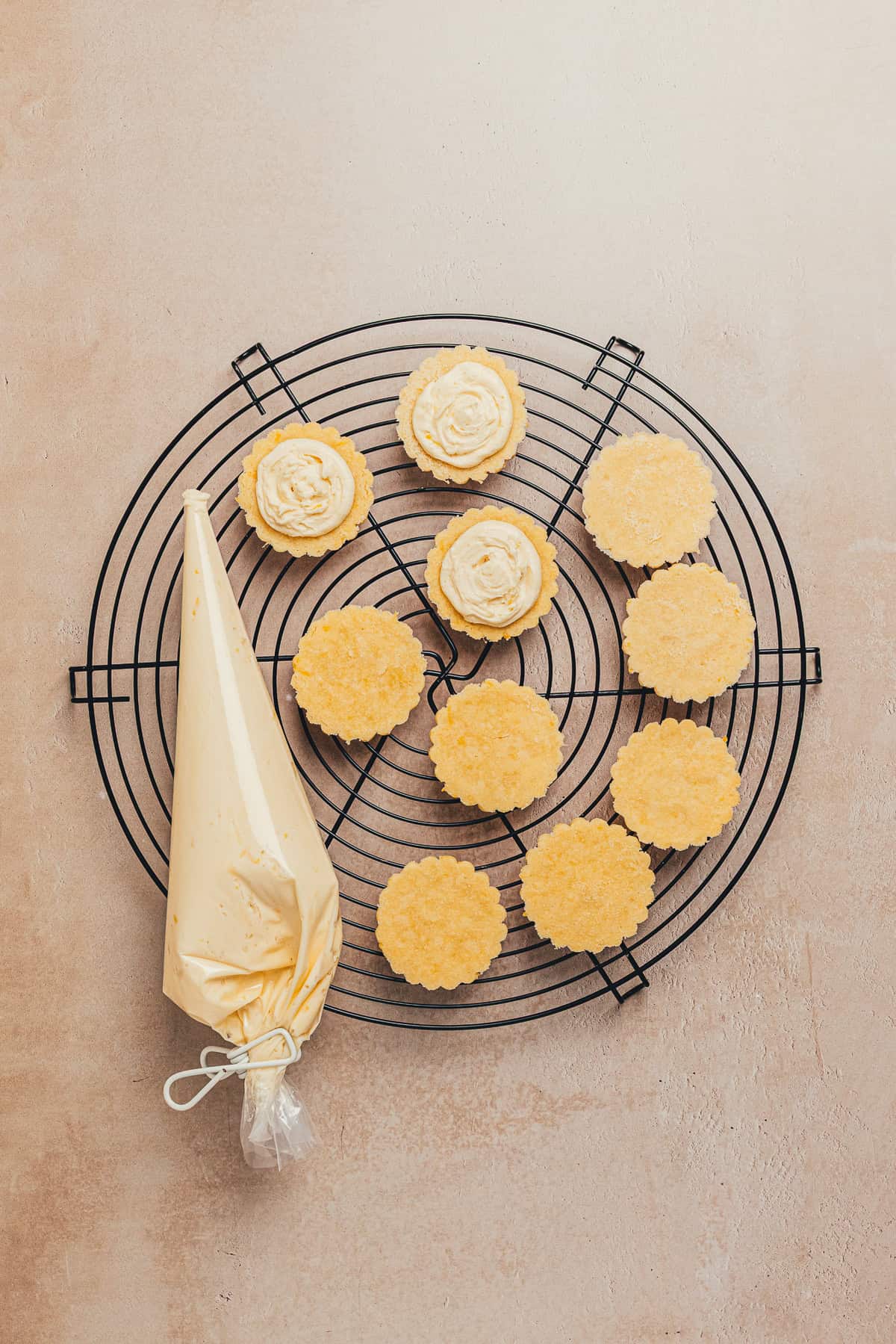 Piping lemon buttercream onto cookies to assemble lemon sandwich cookies.