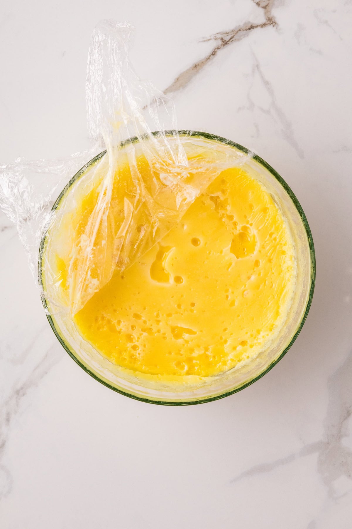 Removing plastic wrap from chilled Instant Pot lemon curd after thickening in the refrigerator.