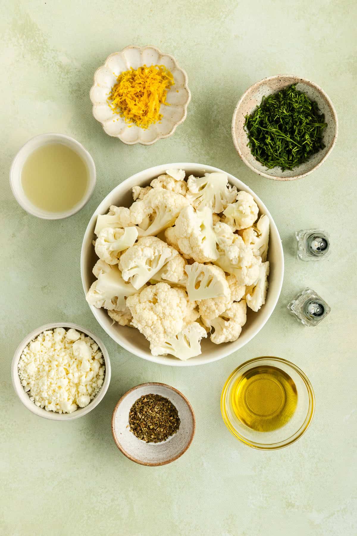 Ingredients for roasted cauliflower with dill and feta including cauliflower florets, lemon, lemon juice, olive oil, dill, feta, oregano, salt, and pepper.