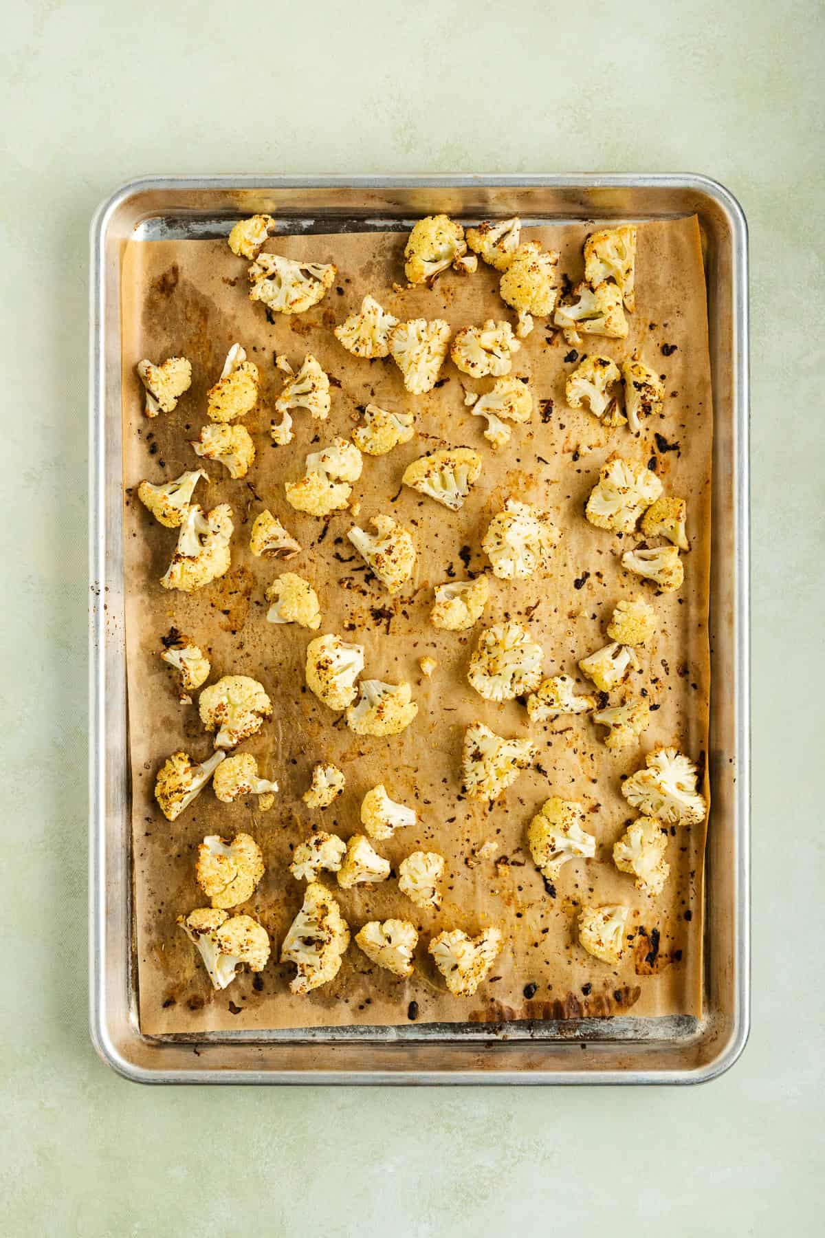 Golden roasted cauliflower florets on a parchment-lined baking sheet.