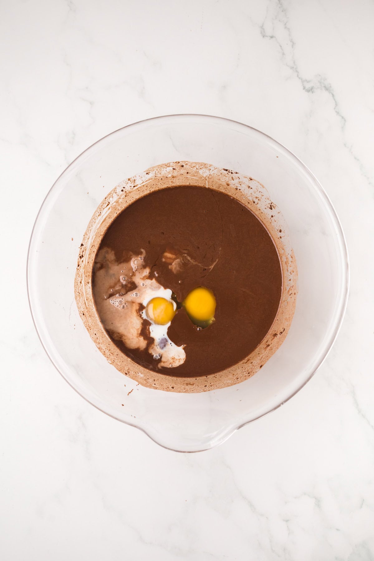 Eggs and milk being added to chocolate cake batter for homemade ding dongs