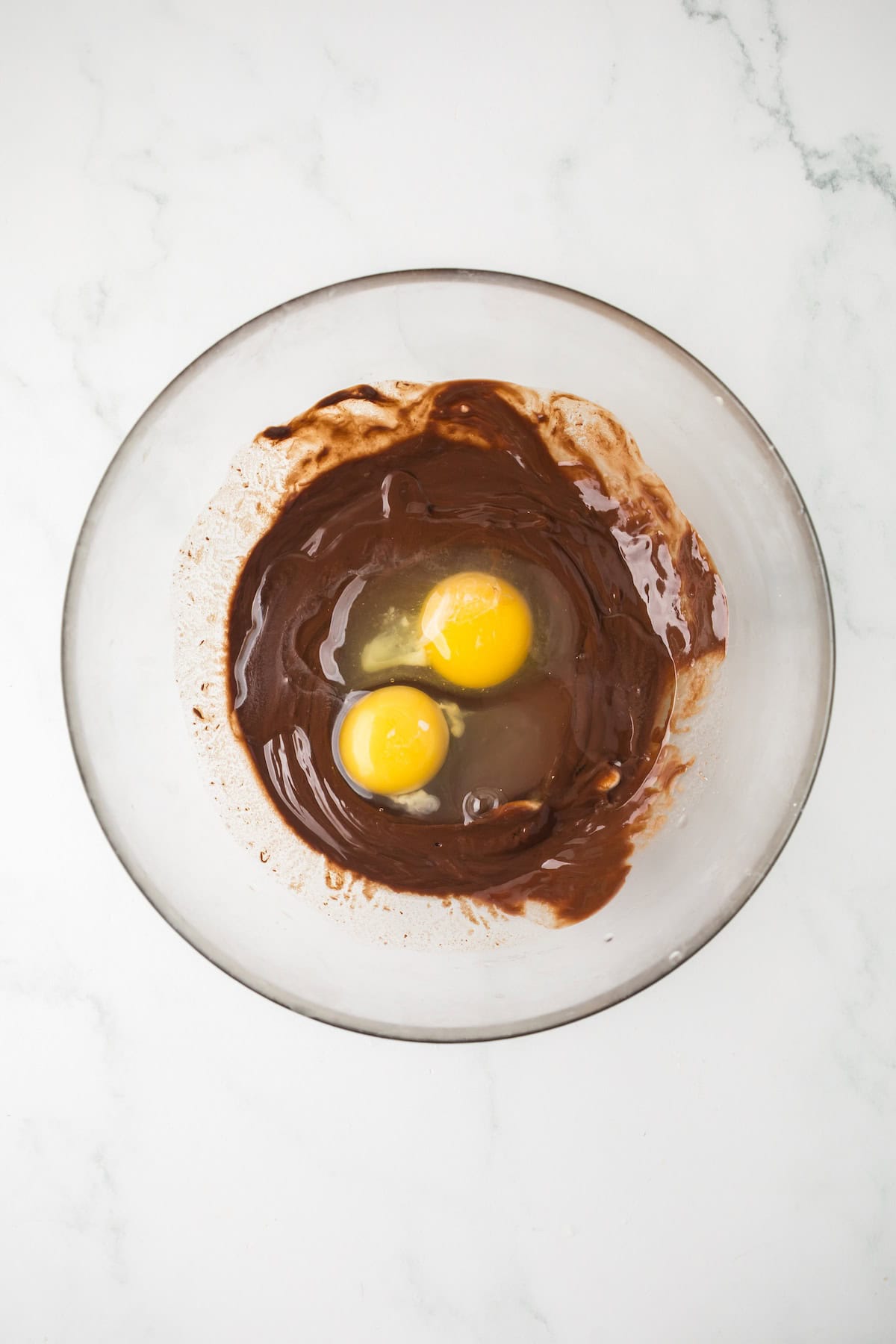 Mixing brownie cookie dough with melted chocolate and eggs in a bowl.