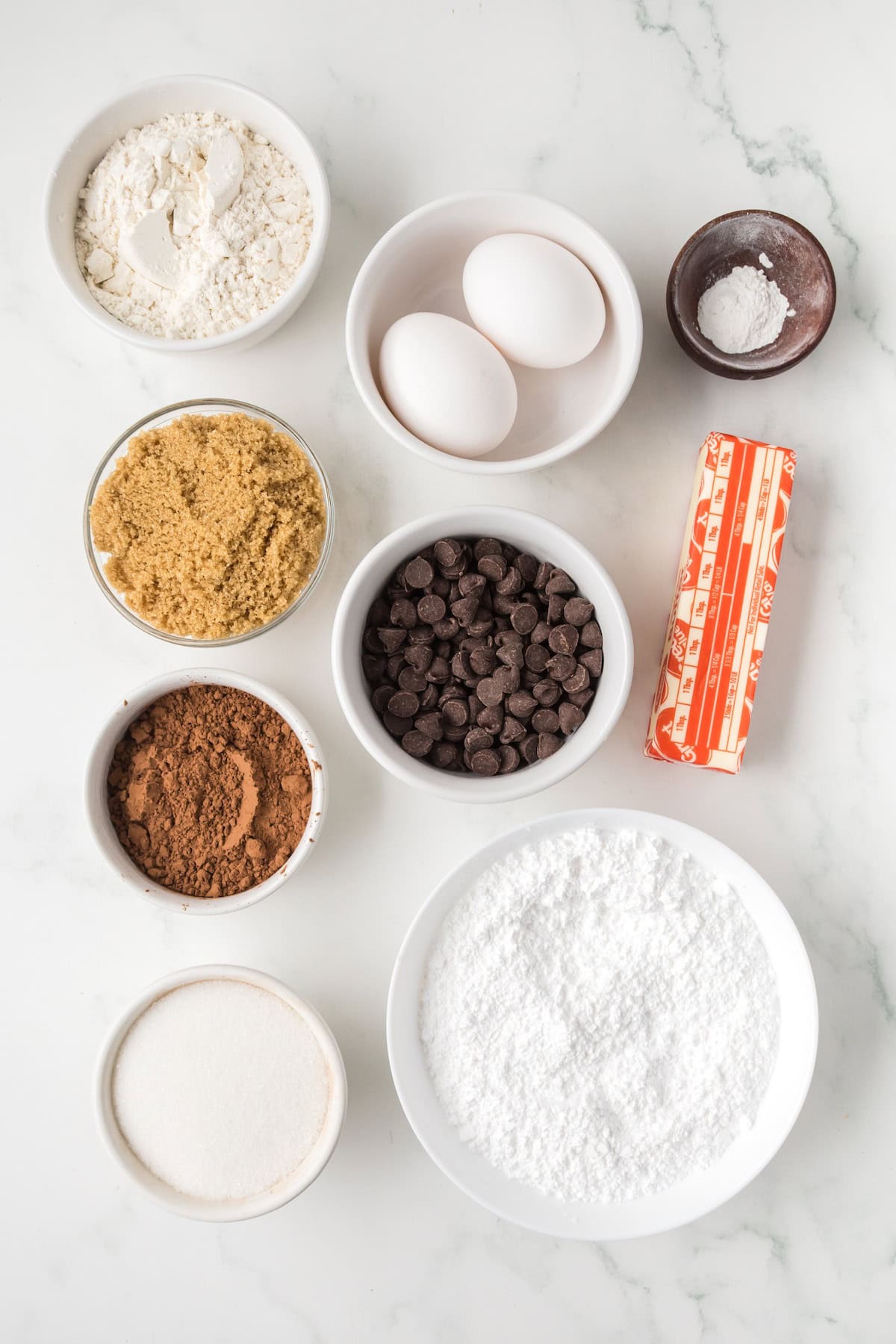 Ingredients for brownie cream pies including cocoa powder, chocolate chips, butter, eggs, and sugar.