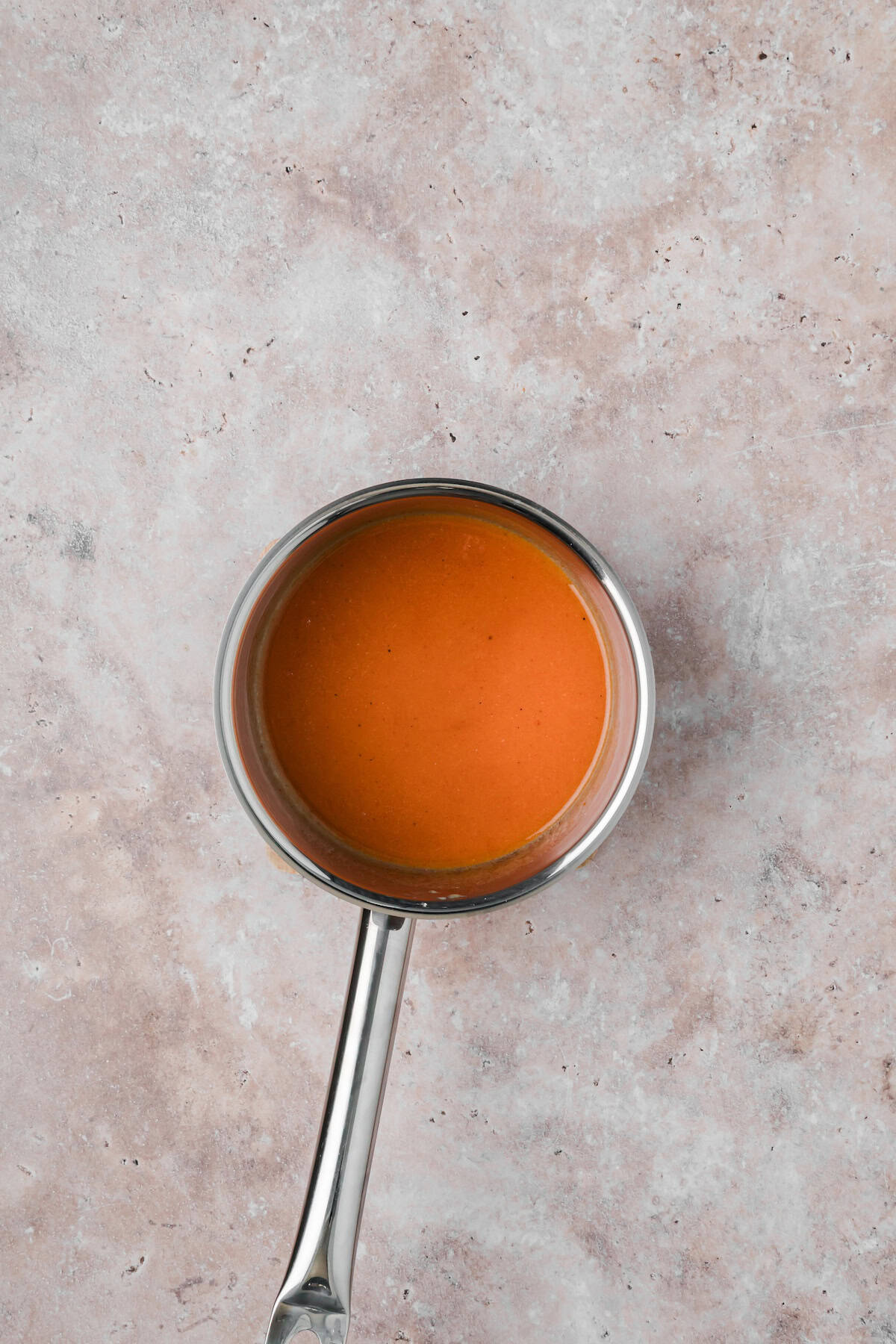 Smooth Cajun buffalo wing sauce in a saucepan after combining butter and hot sauce.