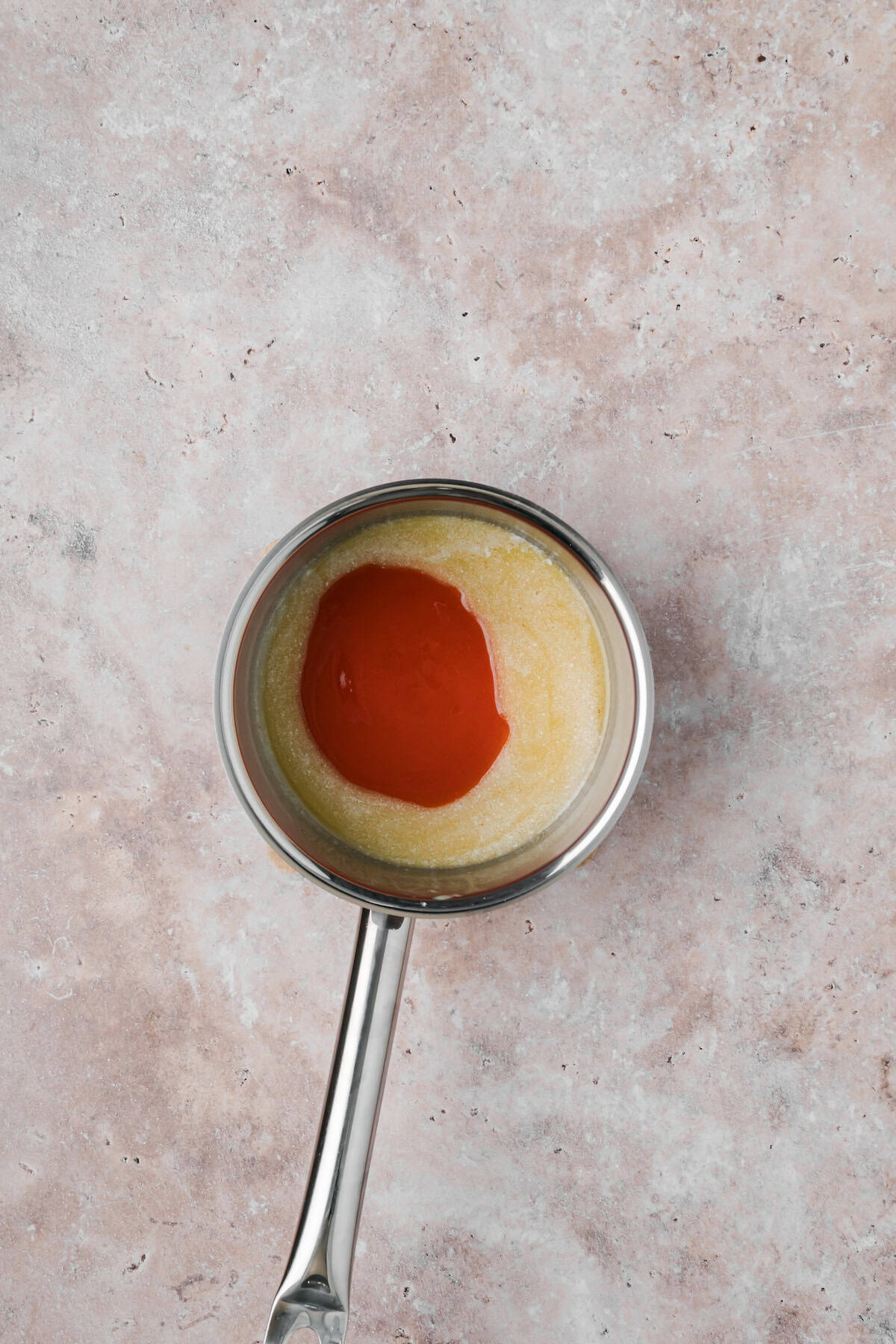 Buffalo Cajun wing sauce made with melted butter and hot sauce in a saucepan.