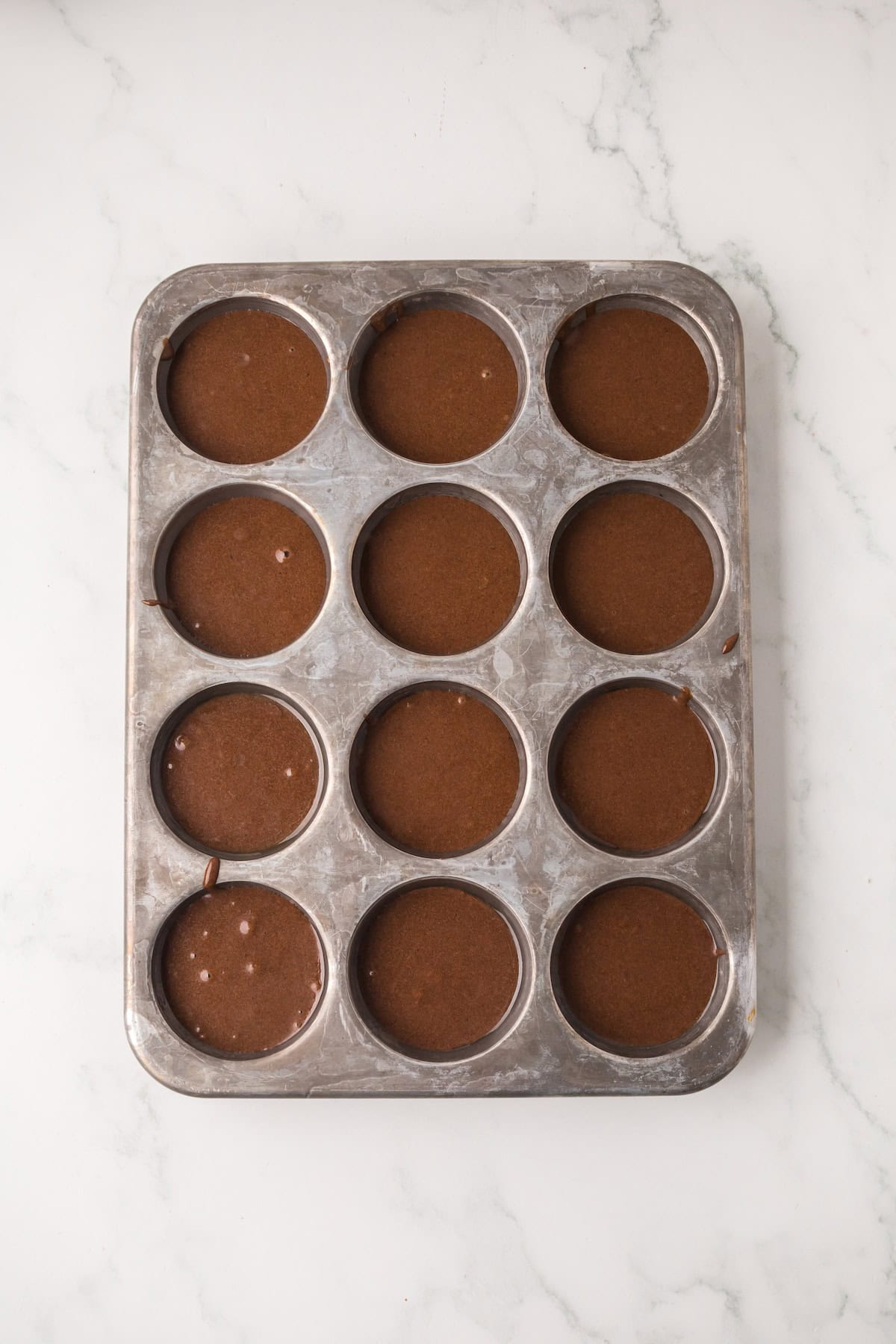 Chocolate cake batter poured into muffin tin for homemade ding dongs.