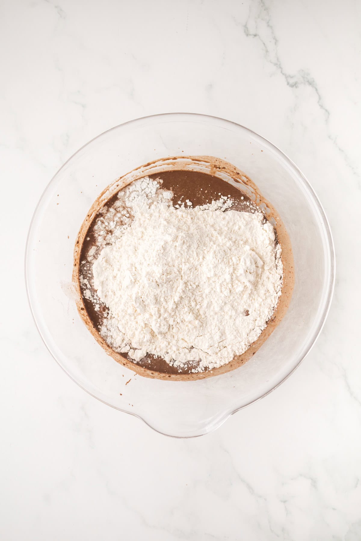 Flour, sugar, and baking powder added to chocolate batter to make homemade ding dongs.
