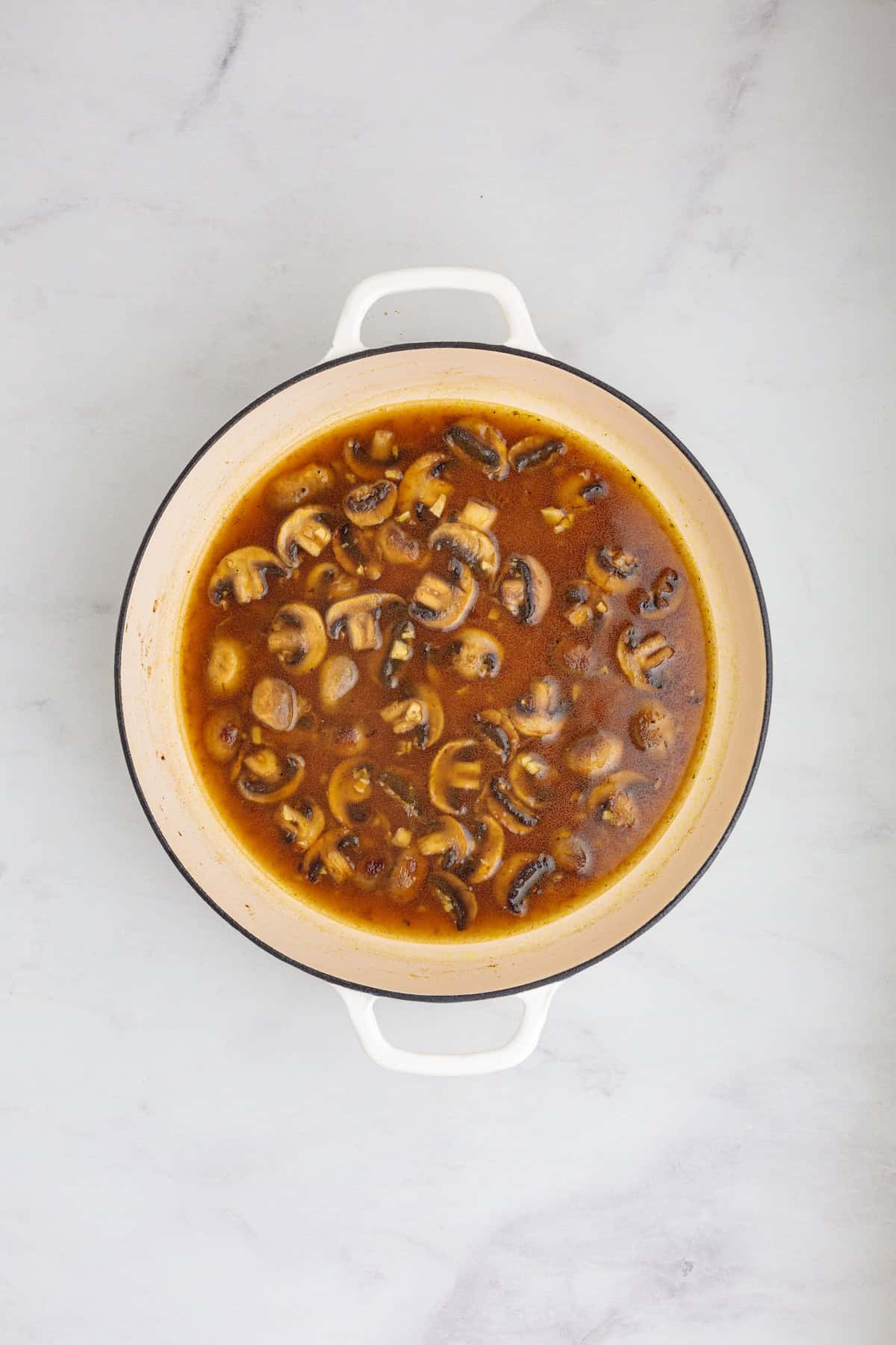 Mushrooms simmering in a savory Marsala wine and chicken broth sauce for creamy chicken Marsala fettuccine pasta.