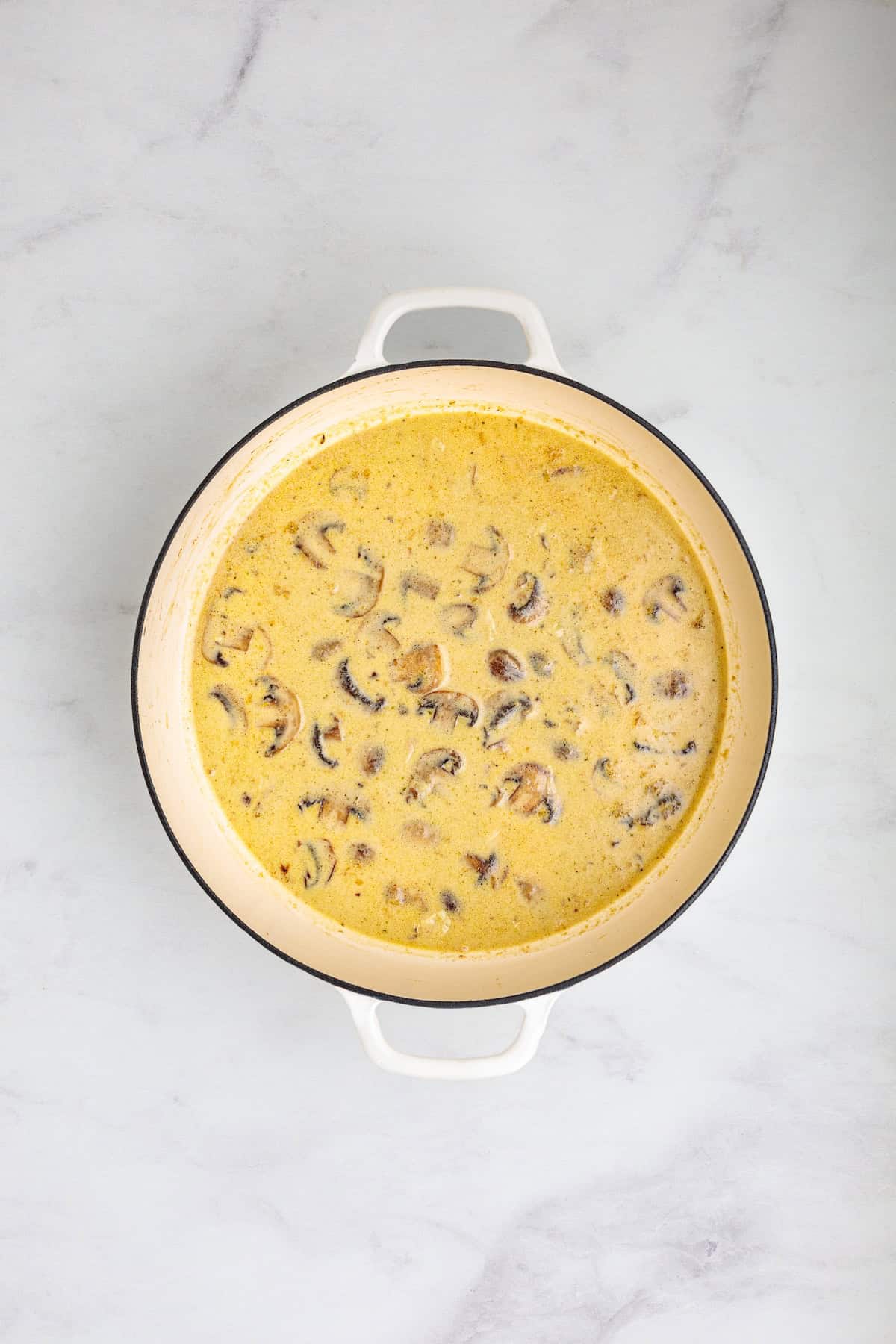 Creamy mushroom Marsala sauce simmering with Parmesan cheese and heavy cream for homemade chicken Marsala fettuccine.